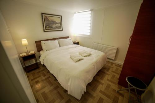 1 dormitorio con 1 cama blanca grande y ventana en Departamento Ovejero, en Punta Arenas