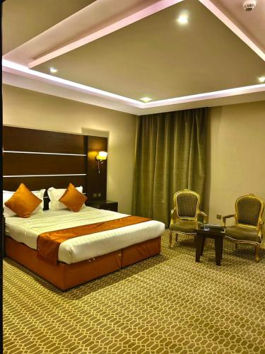 a hotel room with a bed and two chairs at شقق منازل الدانة للشقق المخدومة in Abha