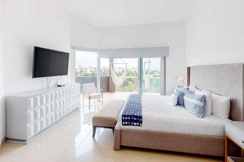 普拉亞德爾卡曼的住宿－Casa Sky 735 Sur @ Mareazul Beachfront，一间白色卧室,配有床和电视