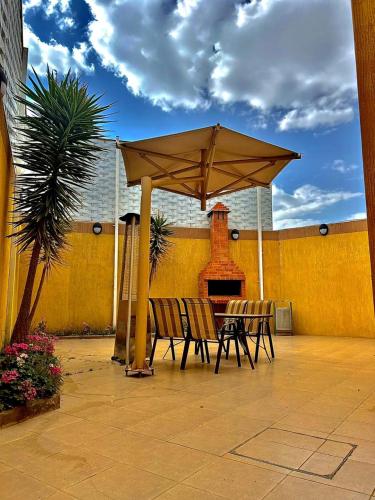 a patio with a table and chairs under an umbrella at شقق منازل الدانة للشقق المخدومة in Abha