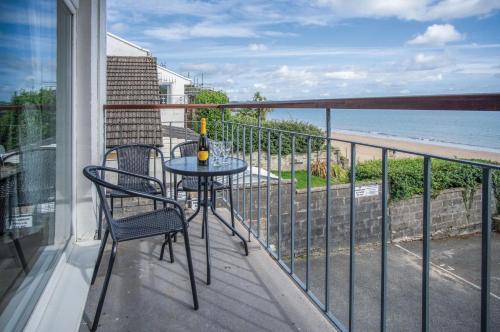 Un balcón con mesa y sillas y el mar. en 17 Beach Court - 2 Bed Apartment - Saundersfoot, en Saundersfoot