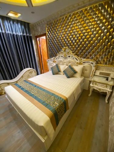 sypialnia z białym łóżkiem z niebiesko-złotą ścianą w obiekcie KEN 2 HOTEL w Ho Chi Minh