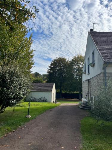 una entrada que conduce a una casa blanca y a un edificio en Studio avec grand jardin + parking en Seraincourt