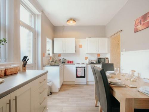 a kitchen with white cabinets and a table with chairs at Halifax Town House - Cosy - Sleeps 5 in Halifax