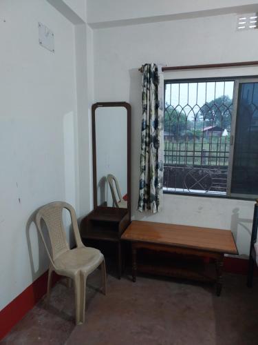 Zimmer mit einem Spiegel, einem Stuhl und einem Tisch in der Unterkunft Lama Residence in Shiliguri