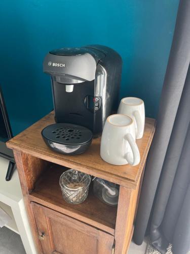 eine Kaffeemaschine und Tassen auf einem Holzständer in der Unterkunft Studio avec grand jardin + parking in Seraincourt