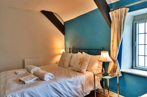 a bedroom with a large bed with a blue wall at Finest Retreats - Clematis Cottage in Stogursey