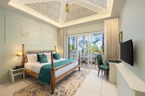 Schlafzimmer mit einem Bett, einem TV und einem Balkon in der Unterkunft WelcomHeritage Santa Roza Kasauli in Kasauli