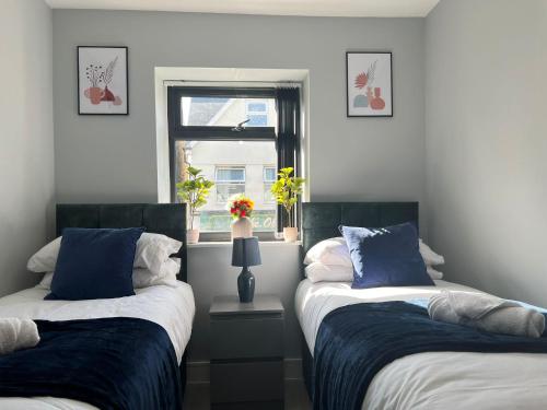2 camas en una habitación con ventana en NEW Modern Flat! Monthly Discount! Near City Centre, en Cardiff