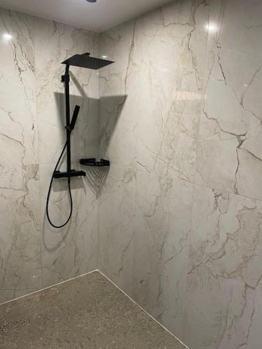 La salle de bains est pourvue d'une douche et d'un mur en marbre. dans l'établissement Quelque part au calme., à Beaumé