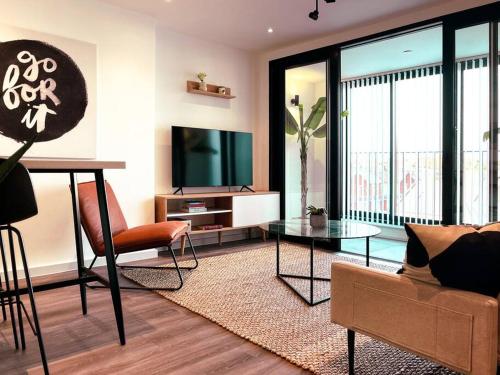 a living room with a couch and a table and a tv at Luxe London Pad with Free Parking in Brentford