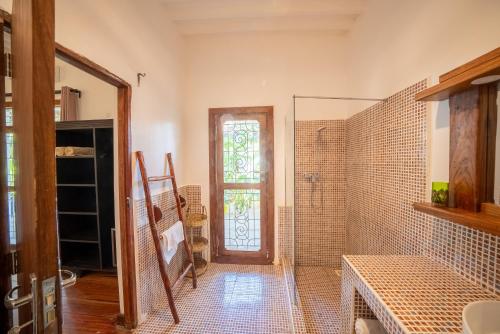 La salle de bains est pourvue d'une douche avec une porte en verre. dans l'établissement Beachfront Turtle House ZanzibarHouses, à Kiwengwa