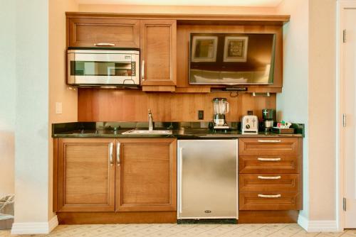 a kitchen with wooden cabinets and a stainless steel refrigerator at Strip View Balcony Suites - No Resort Fee ! in Las Vegas