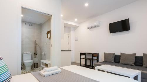 セビリアにあるDolium Apartmentsのベッド、ソファ、テレビが備わる客室です。