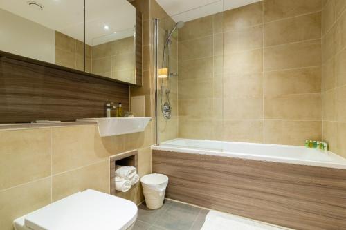 a bathroom with a tub and a toilet and a sink at Divine Suite in London