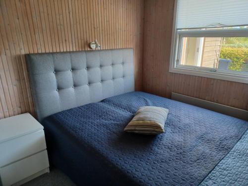 a bedroom with a blue bed with a pillow on it at Øster Hurup in Hadsund