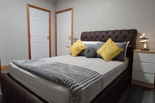 a bedroom with a large bed with yellow pillows at Millhouse Cottage A Luxury 3 bed Bungalow in Antrim