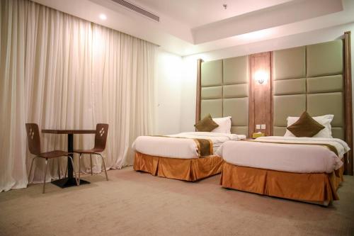 a hotel room with two beds and a table at Areen Hotel Al Basateen in Jeddah