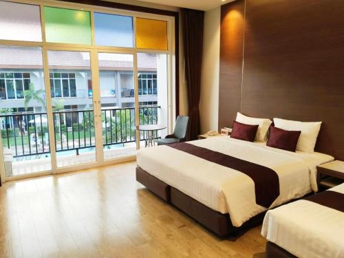 a hotel room with two beds and a large window at Southern Airport Hotel Hatyai in Hat Yai
