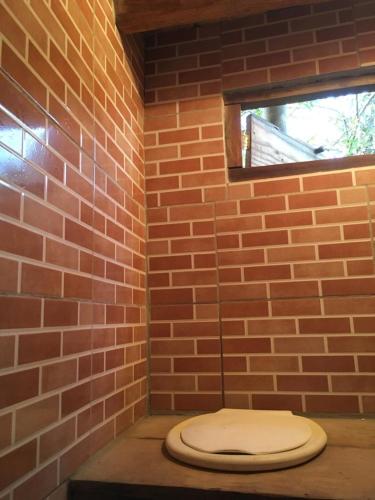 a bathroom with a toilet in a brick wall at Orgânica-Mente B&B in Visconde De Maua