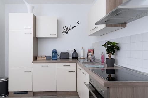 a kitchen with white cabinets and a sink at Ilmpartment - Vollausstattung - Boxspringbett - Wi-Fi - Netflix in Ilmenau