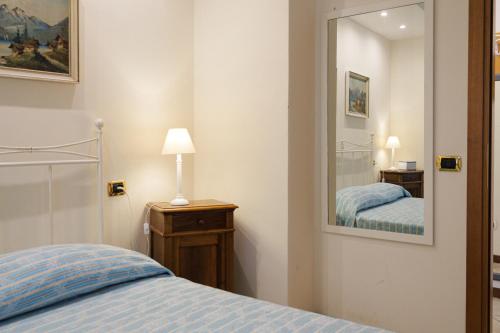 a bedroom with a bed and a mirror at CASA NAVLA' AppartamentI "Ulivi"- "Fiori" -"Velieri"-"Luna"-"Nido"-"Taverna" in Tignale