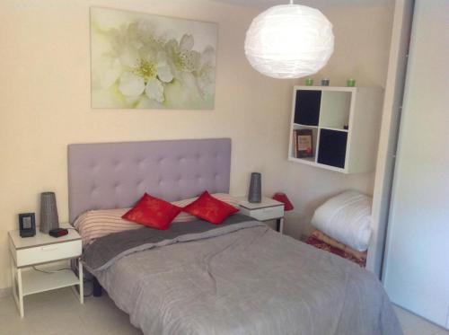 - une chambre avec un lit doté d'oreillers rouges dans l'établissement Appartement charmant à Fréjus, 40 m², proche du jardin, à Fréjus