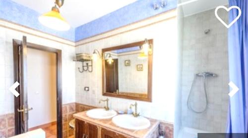 a bathroom with two sinks and a mirror at Charming house in El Bosque + private pool in El Bosque