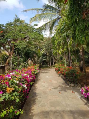 Una pasarela con flores en un jardín en Nyumba Malkia at Tembo Village, en Watamu