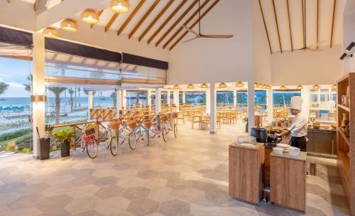 a man standing in a restaurant with tables and chairs at Joy Island Maldives All Inclusive Resort in Male City