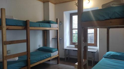 a room with three bunk beds and a window at Albergue Tritón - Villanúa in Villanúa