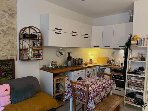 馬賽的住宿－Studio atypique Camas，厨房配有白色橱柜、桌子、桌子和沙发。