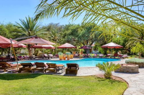 een zwembad met tuinmeubilair en parasols bij Gondwana Namib Desert Lodge in Solitaire