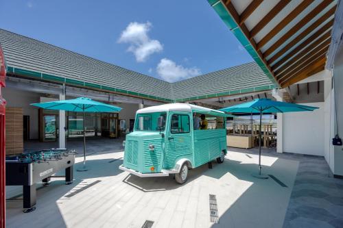 a green van parked in front of a building with umbrellas at Joy Island Maldives All Inclusive Resort in Male City