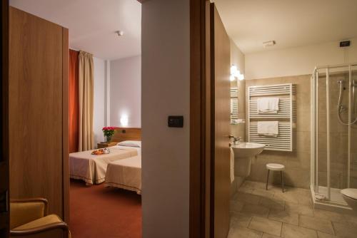 a hotel room with a bed and a bathroom at Hotel Lux in Alessandria