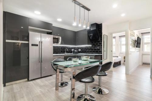 マドリードにあるPlaza España Apartmentのガラスのテーブルと冷蔵庫のあるキッチン