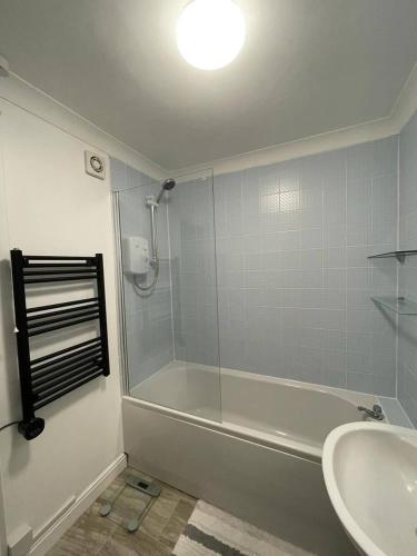 a bathroom with a shower and a tub and a sink at Eaton Ford Green Ground Floor Apartment in Saint Neots