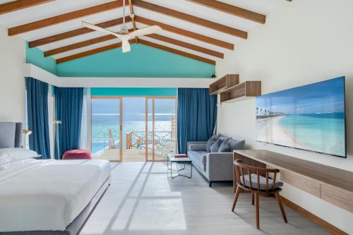 Joy Island Maldives All Inclusive Resort في مدينة ماليه: غرفة نوم مع سرير وإطلالة على المحيط