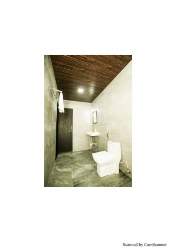 a bathroom with a white toilet and a sink at Coconut Villa in Malavli