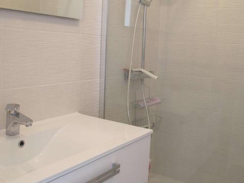 La salle de bains blanche est pourvue d'un lavabo et d'une douche. dans l'établissement Appartement Trébeurden, 3 pièces, 4 personnes - FR-1-368-212, à Trébeurden