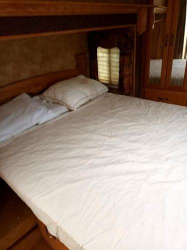 a large white bed in a room with a window at 40' RV Move in Ready in Jordan