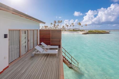 a deck with a lounge chair on the water at Joy Island Maldives All Inclusive Resort in Male City