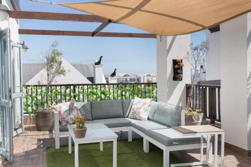 een patio met een bank en tafels op een balkon bij Big Bay Hilltop Villa in Kaapstad