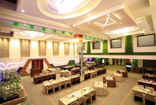 カルナルにあるThe Vivaan Hotel & Resorts Karnalの建物内のテーブルと椅子のあるレストラン