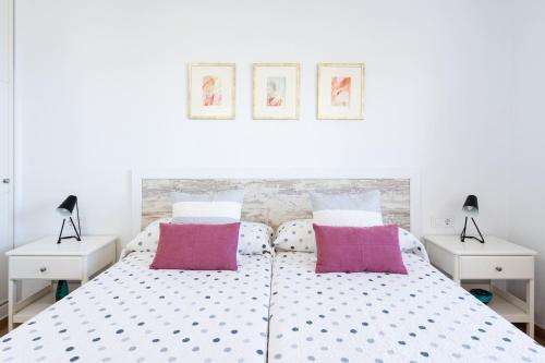 een witte slaapkamer met een groot bed met 2 nachtkastjes bij Casa Los Grabados, piscina, vistas, barbacoa y zen in Icod de los Vinos