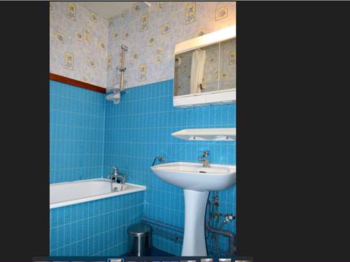 une salle de bain carrelée bleue avec un lavabo et une baignoire dans l'établissement Appartement cosy 2 pièces, terrasse ensoleillée, skis aux pieds, animaux acceptés, Bolquère - FR-1-592-59, à Bolquère-Pyrénées 2000