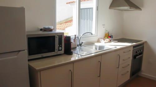 a kitchen with a sink and a microwave at A m a r - 450m from the beach in São Roque