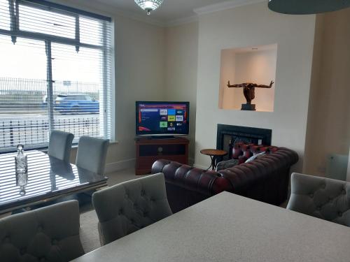 uma sala de estar com um sofá, uma mesa e uma televisão em Victoria Quays Apartments, Fleetwood em Fleetwood