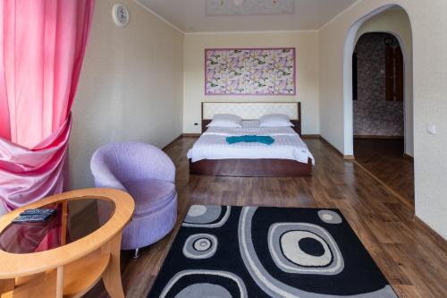 a bedroom with a large bed and a purple chair at Дуглас in Petropavlovsk
