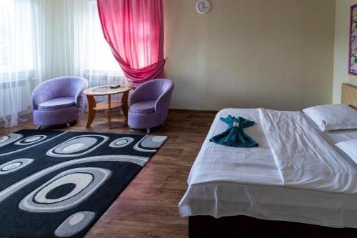 a bedroom with a bed and two chairs and a table at Дуглас in Petropavlovsk